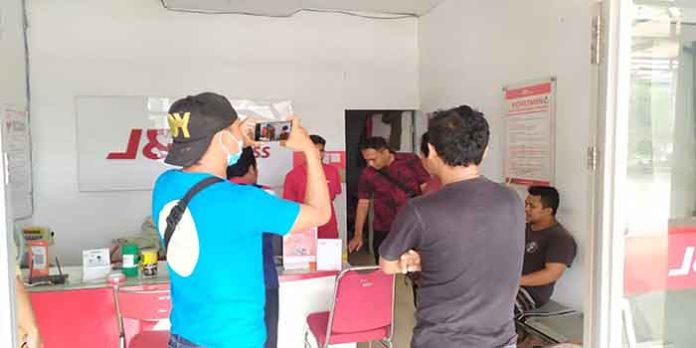 Polisi Menggeledah Paket Kiriman yang Diterima Terduga Pengedar Uang Palsu saat Mengambil Paket di Salah Satu Jasa Pengiriman di Lombok Utara, Senin (31/1/2022).