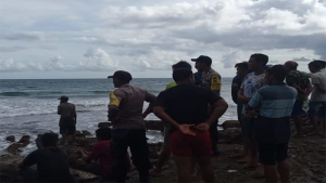 Sejumlah warga dan aparat kepolisian menyaksikan proses pencarian korban menggunakan perahu tradisional di antara terpaan ombak di laut lepas Selatan Kabupaten Bima di Pantai Lere Kecamatan Parado, Minggu (5/3/2023) sore.