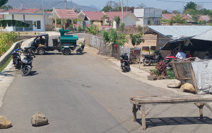 Kondisi ruas jalan yang menghubungkan perumahan Huntap korban banjir bandang tahun 2020 di Desa Tambe Kecamatan Bolo, Kabupaten Bima, Nusa Tenggara Barat, ditutup pemilik lahan yang memprotes program konsolidasi lahan (land consolidation/ LC) karena dianggap mengurangi luas lahan warga, Sabtu (14/10/2023) siang.