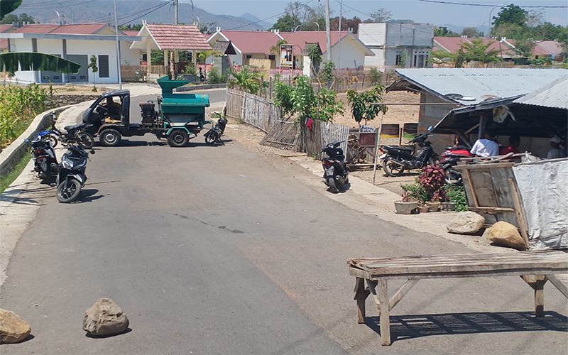 Kondisi ruas jalan yang menghubungkan perumahan Huntap korban banjir bandang tahun 2020 di Desa Tambe Kecamatan Bolo, Kabupaten Bima, Nusa Tenggara Barat, ditutup pemilik lahan yang memprotes program konsolidasi lahan (land consolidation/ LC) karena dianggap mengurangi luas lahan warga, Sabtu (14/10/2023) siang.