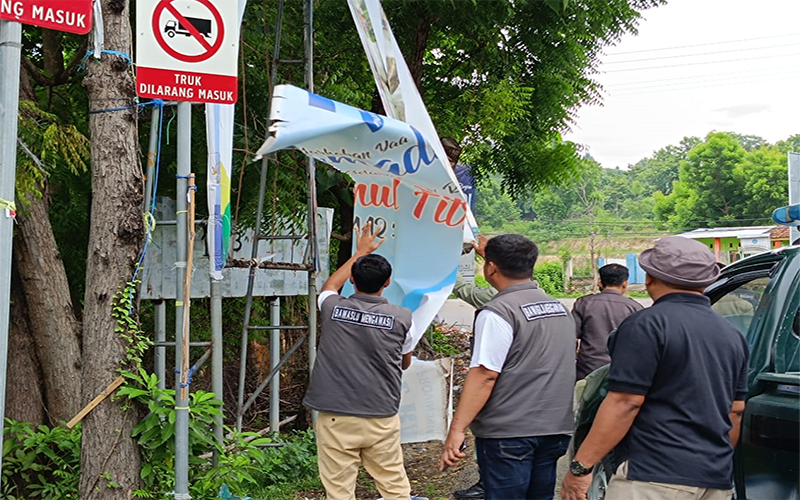 Anggota Bawaslu Kabupaten Bima menertibkan alat peraga kampanye yang masih terpampang di pinggir jalan protocol sekitar Bandara Sultan Muhammad Salahuddin Bima saat masa tenang pemilu 2024, Minggu (11/2/2024).