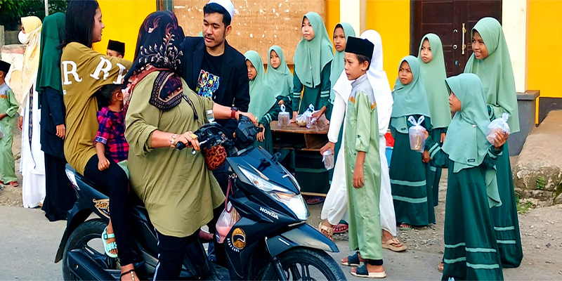Guru pembimbing dan santri-santriwati Rumah Hafidz Al Quran berbasis perpustakaan saat membagikan takjil kepada pengendara yang melintas di depan kantor Desa Sangia Kecamatan Sape Kabupaten Bima, Senin (1/4/2024).