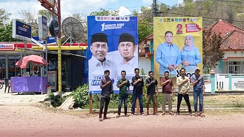 Staf KPU Kabupaten Bima foto di depan baliho yang difasilitasi oleh KPU.