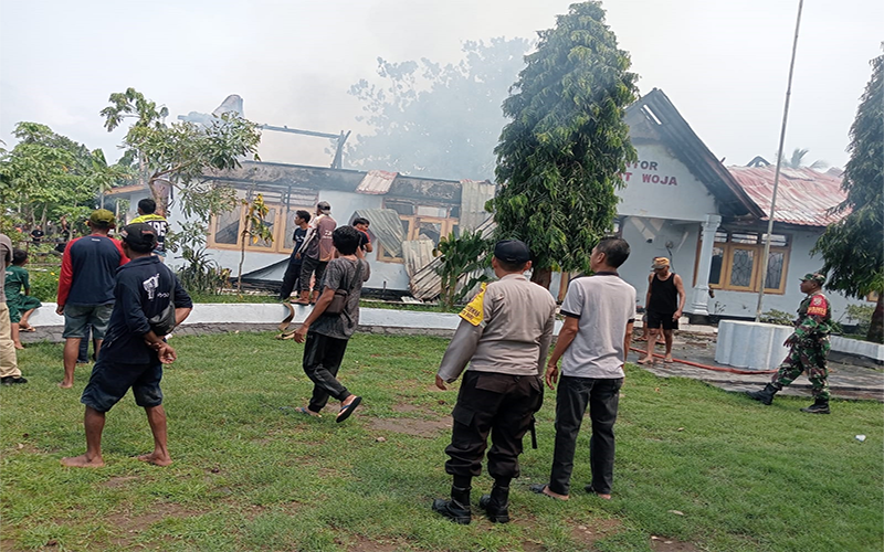 Konsentrasi warga dan aparat keamanan saat berupaya memadamkan api yang melahap kantor Camat Woja Kabupaten Dompu, Minggu (24/11/2024) pagi.