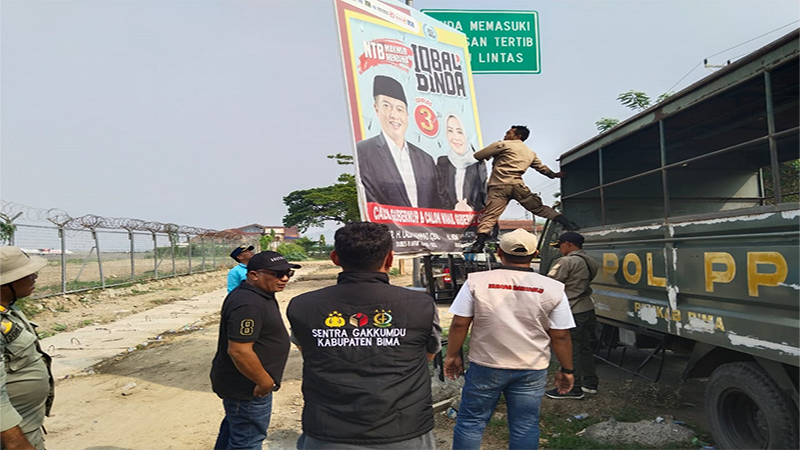 Ketua dan Anggota Bawaslu Kabupaten Bima mengawasi proses penertiban alat peraga kampanye oleh personil Satuan Polisi Pamong Praja di sekitar Bandara Sultan Muhammad Salahuddin Bima, Minggu (24/11/2024).