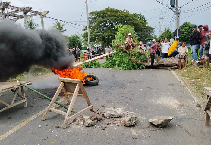 Kondisi ruas jalan negara Lintas Bima-Sumbawa yang ditutup massa Jumat (20/6/2025) siang. Massa yang dipimpin ibu korban penganiayaan menuntut terduga pelaku penusukan pelajar ditangkap.