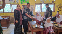Camat Sape, Muhammad Akbar menyerahkan paket Makan Berigizi Gratis saat penyaluran MBG perdana di sejumlah satuan pendidikan di Kecamatan Sape Kabupaten Bima, Nusa Tenggara Barat, Kamis (21/8/2025).