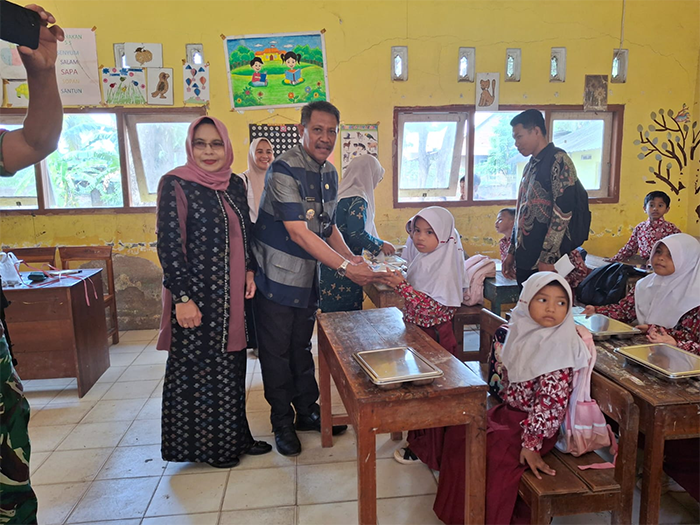 Camat Sape, Muhammad Akbar menyerahkan paket Makan Berigizi Gratis saat penyaluran MBG perdana di sejumlah satuan pendidikan di Kecamatan Sape Kabupaten Bima, Nusa Tenggara Barat, Kamis (21/8/2025).