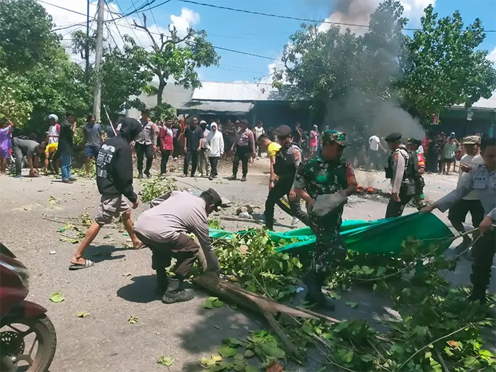 Aparat keamanan saat berupaya mengangkat dan membersihkan materia yang menutup ruas jalan Lintas Bima-Sumbawa di persimpangan Desa Darusalam Kecamatan Bolo Kabupaten Bima, Sabtu (6/12/2025) siang.