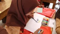 Nabila Alisa Putri berupaya menyelesaikan gambar di tengah keterbatasannya melihat.