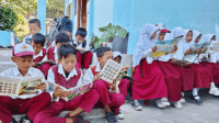 Siswa SDN Sowa Kecamatan Soromandi, Muhammad Ifan dan kawan-kawannya antusias membaca buku cerita yang didistribusikan YAPPIKA dan YISA Ambalawi di sela menunggu peresmian perpustakan sekolah, Senin (11/5/2026). Foto US/ Berita11.com.