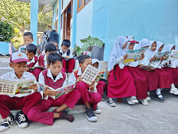 Siswa SDN Sowa Kecamatan Soromandi, Muhammad Ifan dan kawan-kawannya antusias membaca buku cerita yang didistribusikan YAPPIKA dan YISA Ambalawi di sela menunggu peresmian perpustakan sekolah, Senin (11/5/2026). Foto US/ Berita11.com.